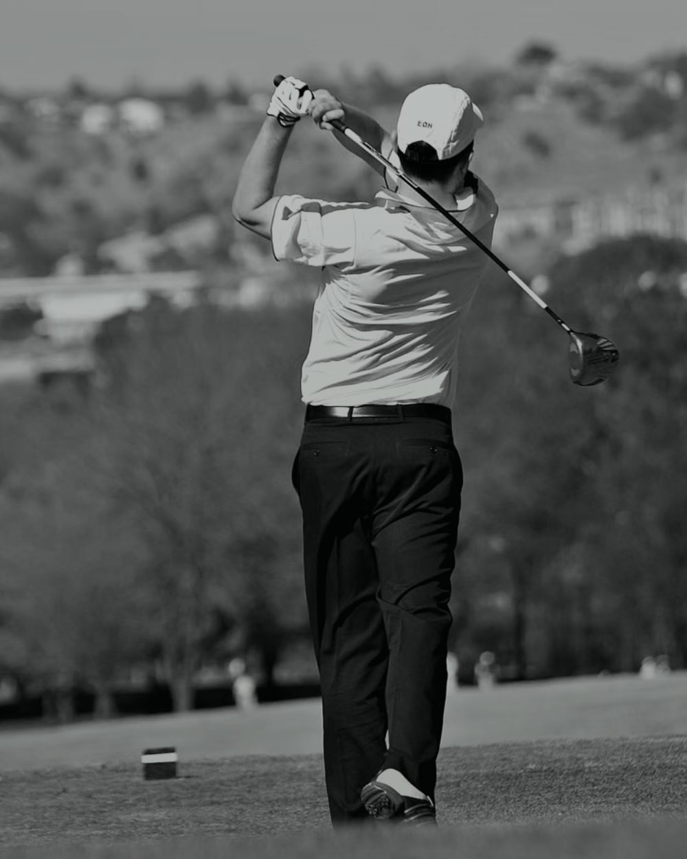 A golfer held at the top of the follow-through, monochrome