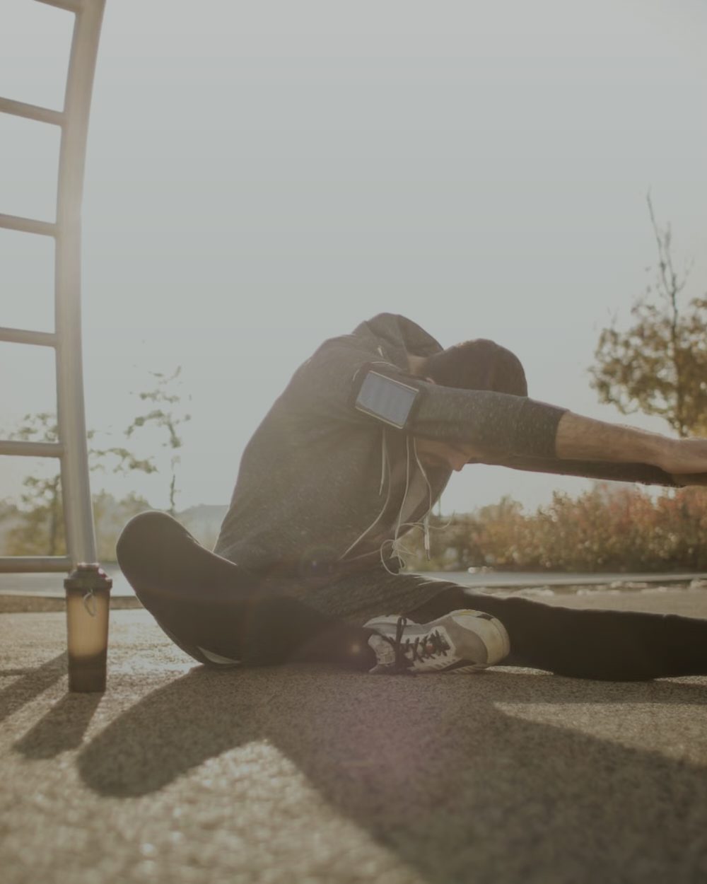 An athlete holding a deep low stretch outdoors in backlight